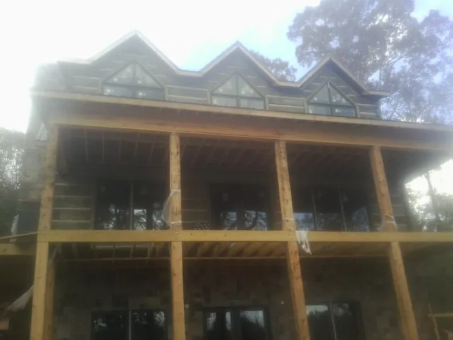 Dormers and porch framing on a large log home under construction — Roof Coating work by our crew in Hays