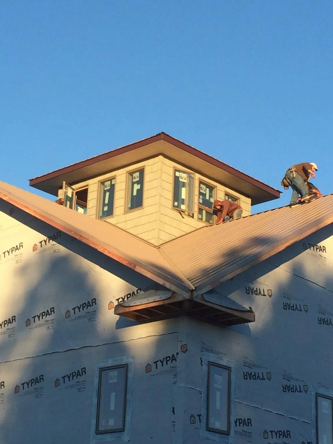Roofers working around a rooftop cupola on a new metal roof at sunset — Roof Waterproofing in Hays by Roofing Brothers